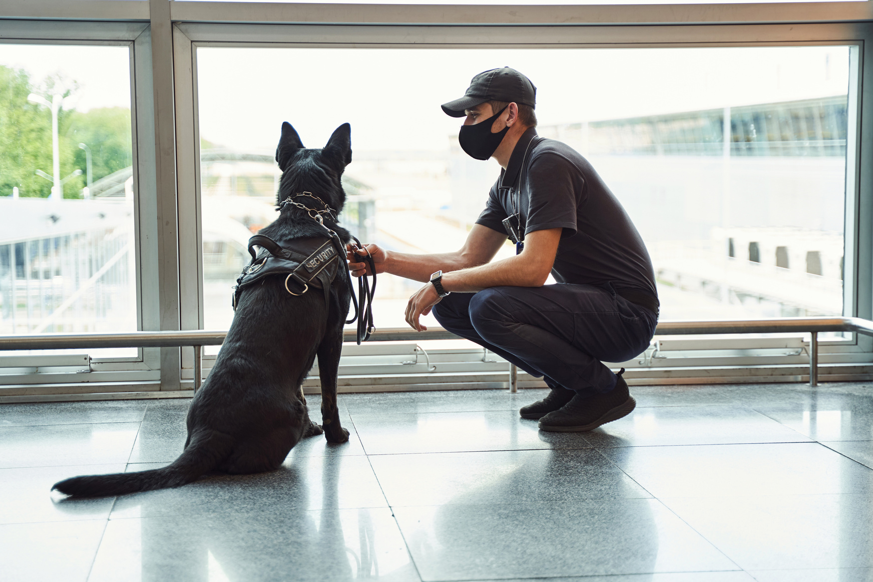 Security officer with detection dog patrolling airport terminal